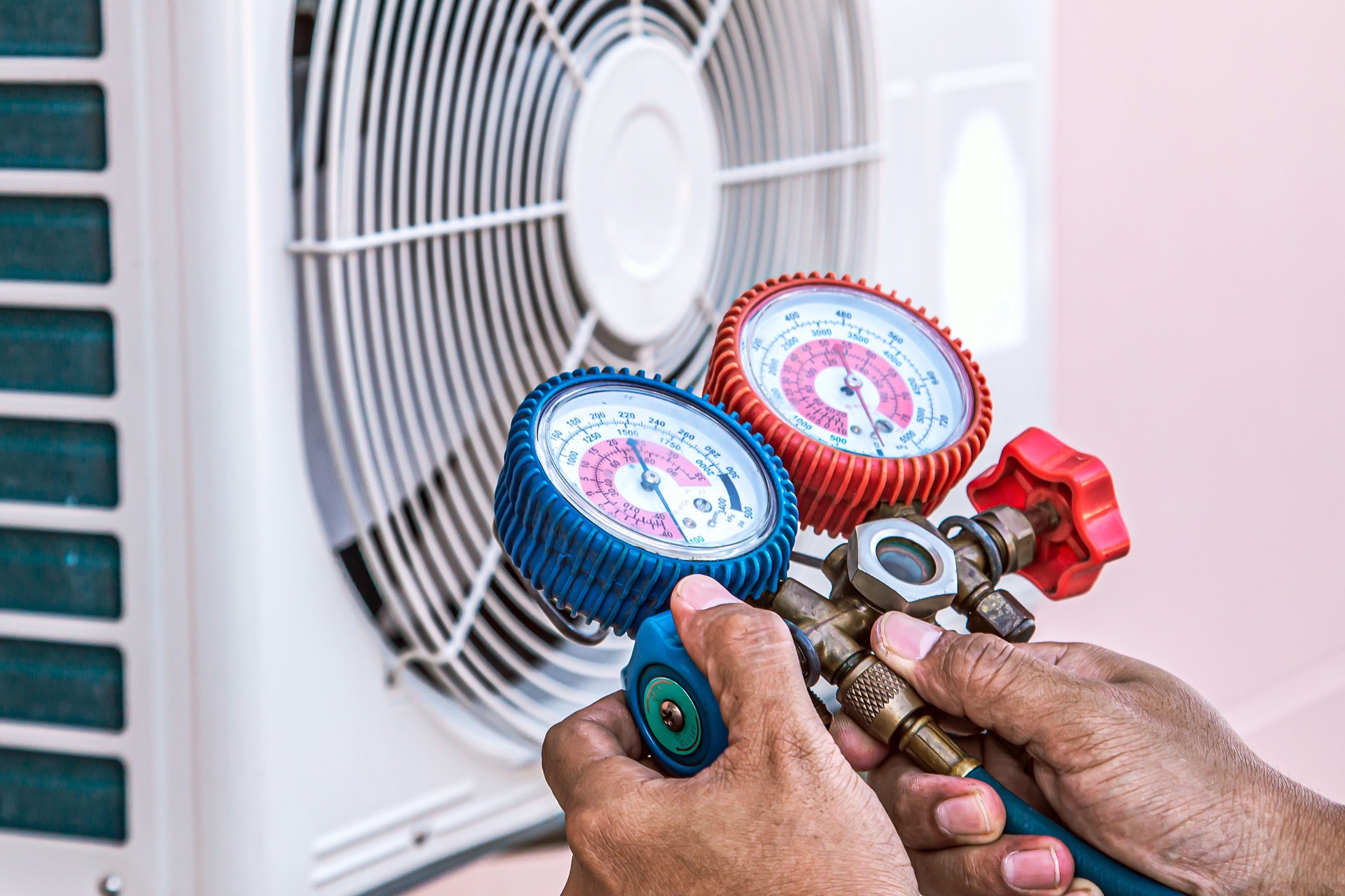 Mechanic air repair using manifold gauge for filling home air conditioner and checking maintenance outdoor air compressor unit.